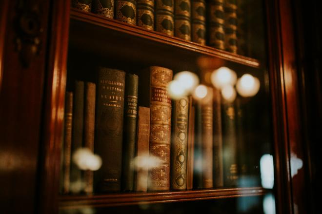 Antique leather-bound legal volumes behind glass in a lamplit bookcase
